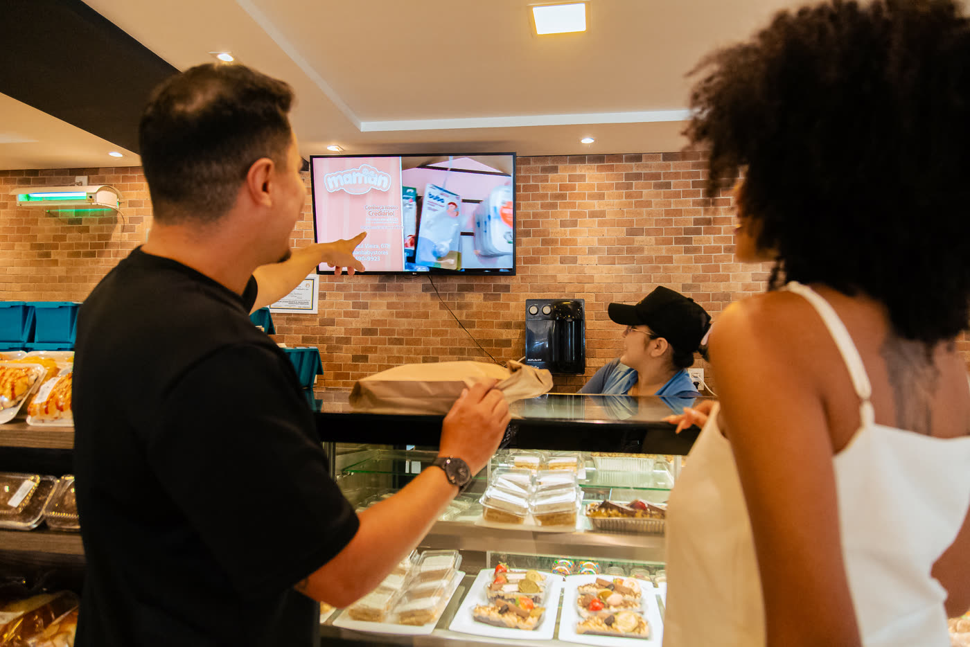 Cliente no balcão apontando para a tela do estabelecimento